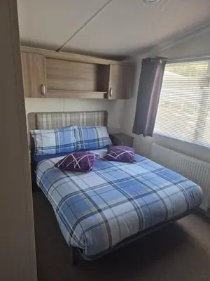 a small bedroom with a bed and a window at Lovely Caravan With Front Decking At Carlton Meres Park Ref 60018R in Saxmundham