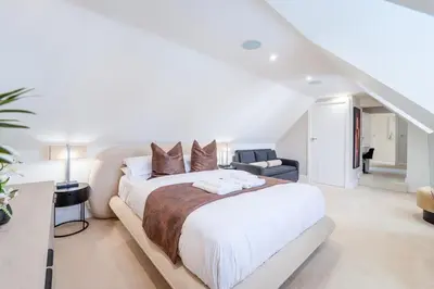 a white bedroom with a large bed and a staircase at Emerson Park Villa, Heated Pool, Hot Tub, Cinema in Harold Wood