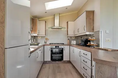 a large kitchen with white appliances and wooden floors at Finest Retreats - Pembroke Luxury Lodge
