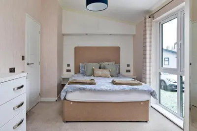 a bedroom with a large bed with a large window at Finest Retreats - Churchill Luxury Lodge