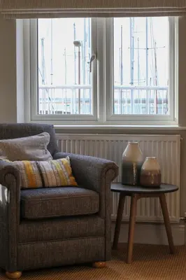 a living room with a chair and a table and a window at The Victory at Mersea in West Mersea