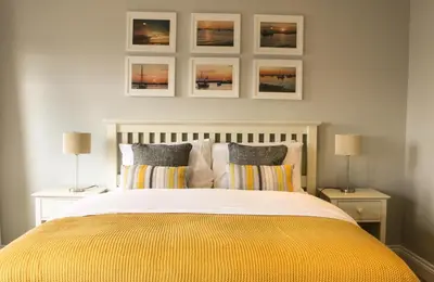 a bedroom with a bed with three pictures on the wall at The Victory at Mersea in West Mersea