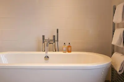 a bath tub with a faucet and two bottles on it at The Victory at Mersea in West Mersea