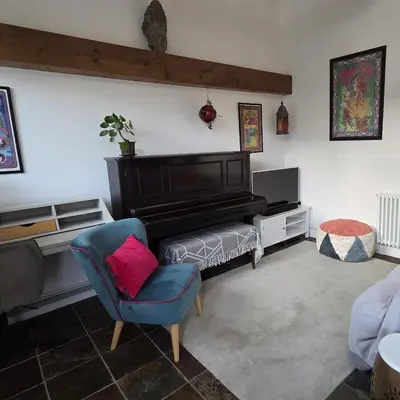 a living room with a piano and a chair at The Old Stables in Felixstowe