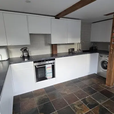 a kitchen with white cabinets and a washing machine at The Old Stables in Felixstowe