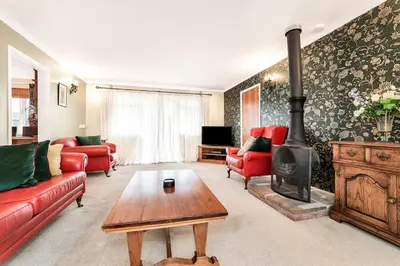 a living room with red furniture and a wood stove at 2-Bed Home with Free Parking - 2 min Walk to Bus in Cherry Hinton
