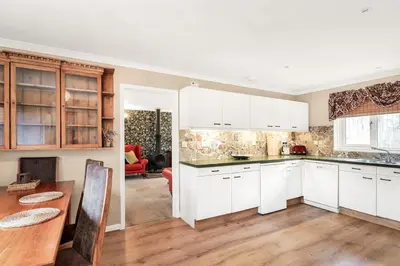 a kitchen with white cabinets and a wooden table at 2-Bed Home with Free Parking - 2 min Walk to Bus in Cherry Hinton