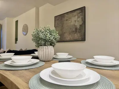 a wooden table with white bowls and plates on it at 2 bed house secure parking Sleeps 6 in Ipswich