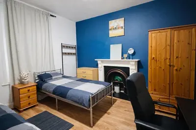 a bedroom with blue walls and a bed and a fireplace at landvue stays, The Colchester town White House 4 bed 2 bath! in Mundon