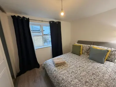 a bedroom with a bed with black curtains and a window at BMC Serene Spacious 1BR Flat in Enfield
