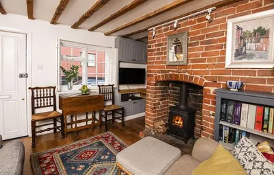 a living room with a brick fireplace and a table and chairs at 4 Angel Lane in Woodbridge
