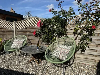 a patio with two chairs and a table and roses at 4 Angel Lane in Woodbridge
