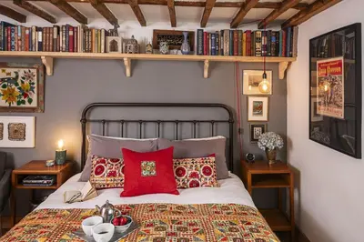 a bedroom with a bed with red pillows and books at 4 Angel Lane in Woodbridge