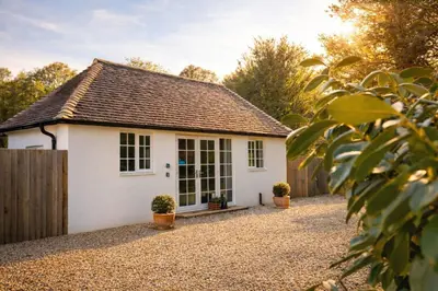 a white cottage with a fence and potted plants at Greenacres in Kelsale