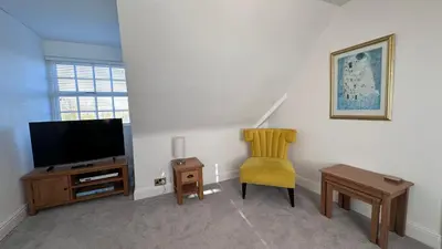 a living room with a tv and a chair at The Coach House WPH, Epping in Epping