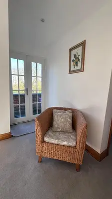 a wicker chair with a pillow sitting in a room at The Coach House WPH, Epping in Epping