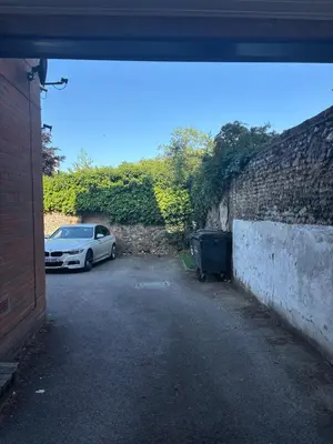 a car parked in a parking lot next to a brick wall at Lavish The White Apartment in Bury Saint Edmunds