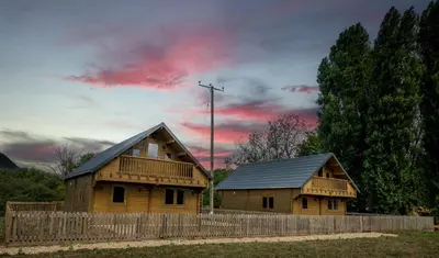 two wooden houses with a fence and a cloudy sky at Buzzards Retreat in Larling