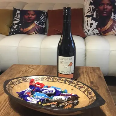 a bottle of wine and a plate of candy on a table at Norwich New 3 Bedroom Townhouse Close to NNUH UEA