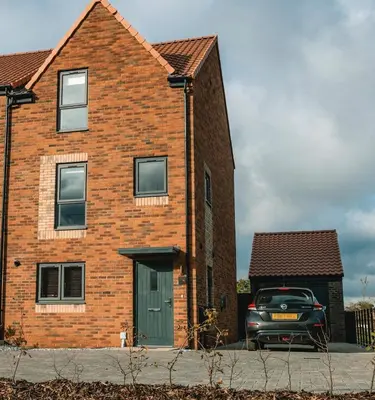 a brick house with a car parked in front of it at Norwich New 3 Bedroom Townhouse Close to NNUH UEA