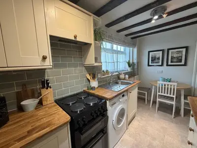 a kitchen with a stove top oven next to a sink at Pretty Cottage in Harleston, Norfolk, dog friendly in Harleston