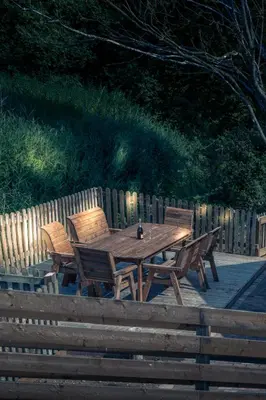 a wooden picnic table with three wooden chairs around it at Owls Nest in Larling