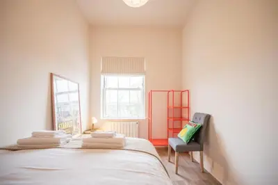 a bedroom with a bed and a chair and a window at Luxury Leiston 2 bed 2 bath with parking in Leiston