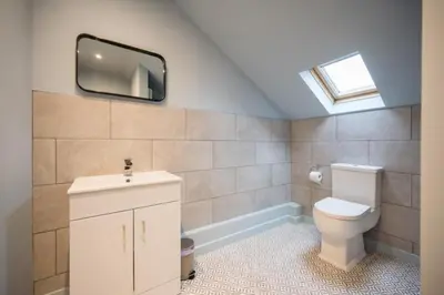 a bathroom with a toilet and a tv on the wall at Luxury Leiston 2 bed 2 bath with parking in Leiston