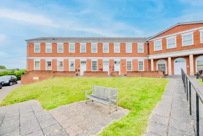 a bench sitting in the grass in front of a building at Luxury Leiston 2 bed 2 bath with parking in Leiston