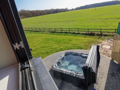 a hot tub on a patio with a view of a field at The Corn Silo in Ipswich