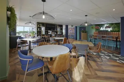 a restaurant with tables and chairs and a bar at Travelodge Cambridge Orchard Park in Milton