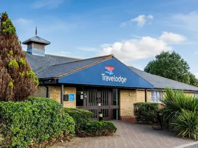 a hotel with a blue sign on the front of it at Travelodge Colchester Feering in Feering