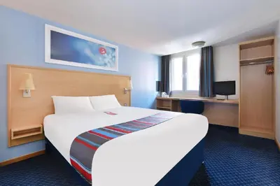 a hotel room with a large bed and a desk at Travelodge Colchester Feering in Feering