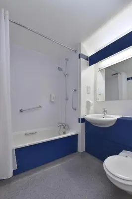a blue and white bathroom with a sink and a toilet at Travelodge Colchester Feering in Feering