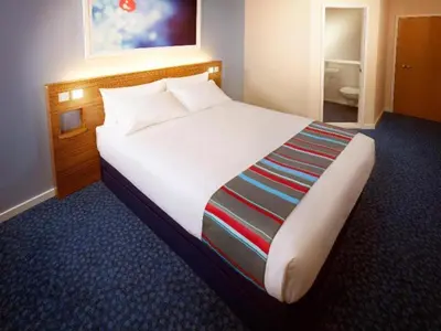 a large white bed in a hotel room at Travelodge Colchester Feering in Feering