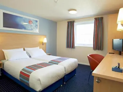 a hotel room with a bed and a desk at Travelodge Colchester Feering in Feering