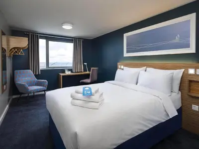 a bedroom with a large bed with towels on it at Travelodge Cambridge Swavesey in Bar Hill