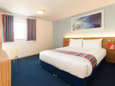 a hotel room with a large bed and a desk at Travelodge Huntingdon Fenstanton in Fenstanton
