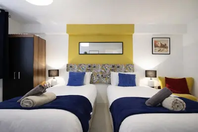 a hotel room with two beds and a yellow wall at Central Location Stylish 1-Bed Apartment Free Parking in Colchester
