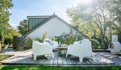 a patio with white chairs and a table at Blackshore House in Wenhaston