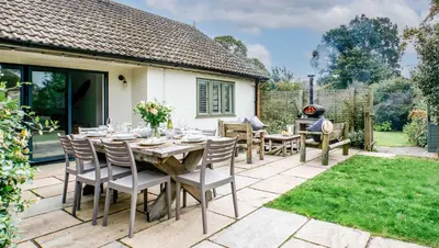 a patio with a table and chairs and a grill at Blackshore House in Wenhaston