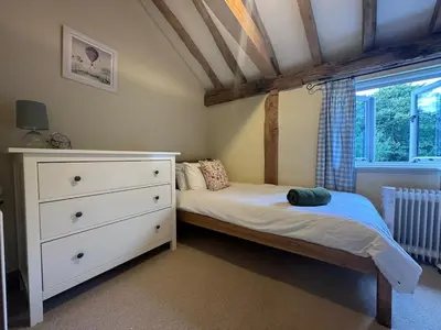 a bedroom with a bed and a dresser and a window at Stunning converted barn - Brand sleeps 8 in Sutton