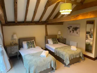 a bedroom with two beds and a ceiling at Stunning converted barn - Brand sleeps 8 in Sutton