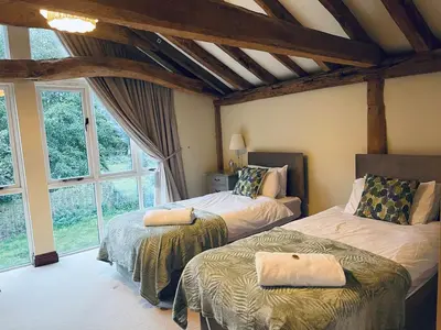 a bedroom with two beds and a large window at Stunning converted barn - Brand sleeps 8 in Sutton