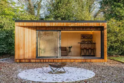a small wooden shed with a bench in a yard at Bressingham Lodge by Leap Escapes in Diss