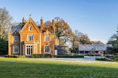 a large orange house with a large grass yard at Bressingham Lodge by Leap Escapes in Diss