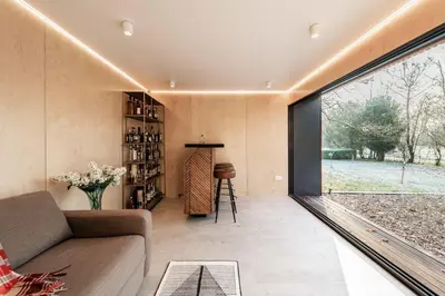 a living room with a couch and a large window at Bressingham Lodge by Leap Escapes in Diss