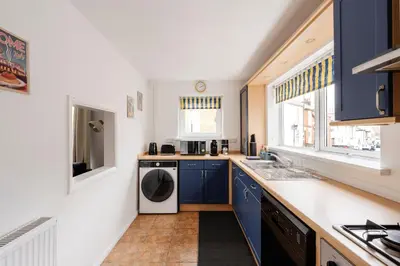 a kitchen with blue cabinets and a washer and dryer at La Casa Bianca in Bury Saint Edmunds