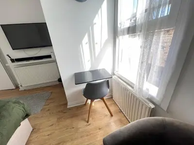 a living room with a chair in front of a window at Queens - Cosy Central Apartment - JTAP Properties in Cambridge
