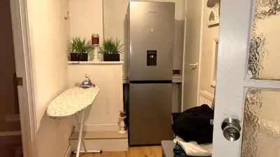 a small kitchen with a refrigerator and a table at Serene Guest Retreat in Basildon Comfort and Convenience Await in Basildon